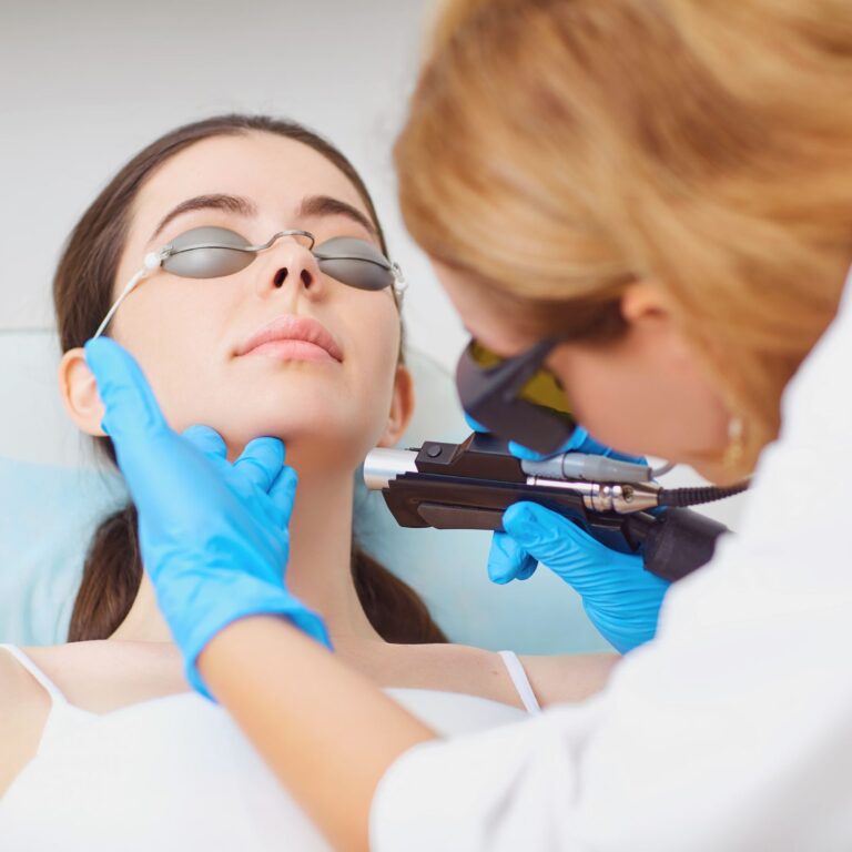 Aesthetic doctor performing facial laser treatment client is wearing metal laser protective block out goggles