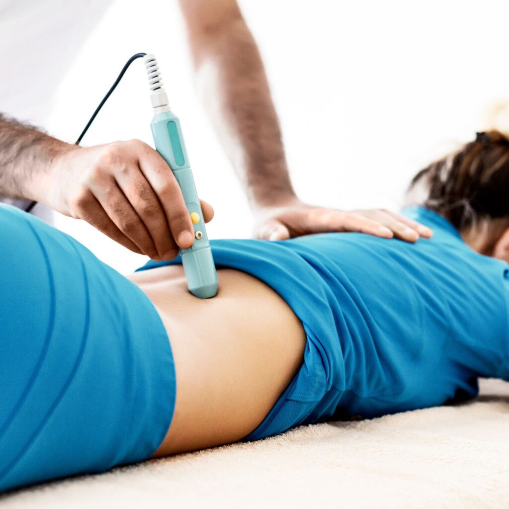 Chiropractor treating a patient's lumbar with laser therapy